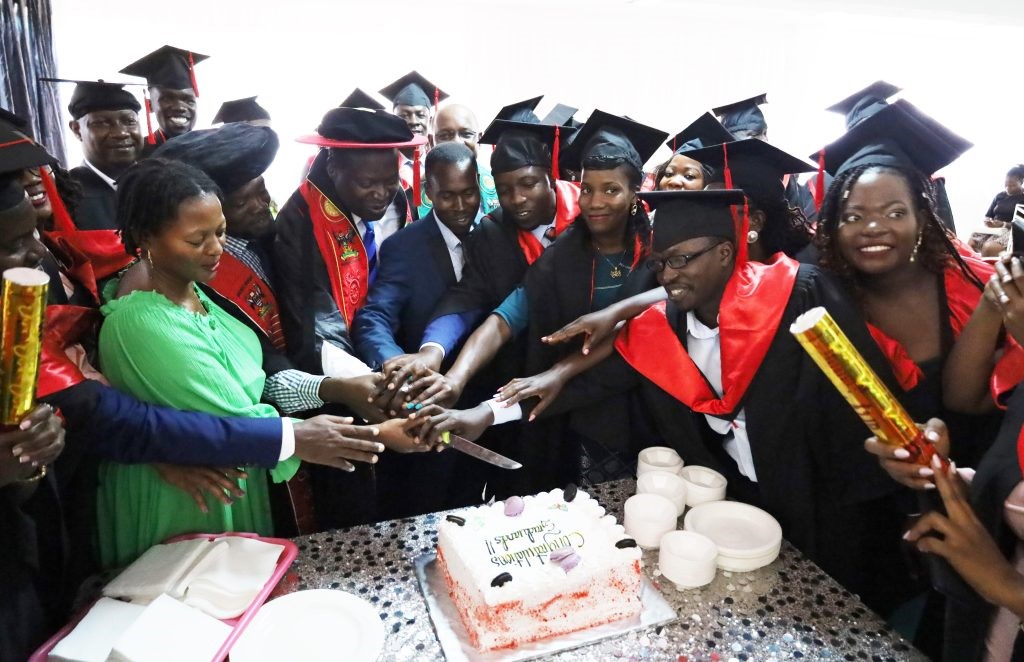 Members of the College management and graduants cutting the cake to symbolize the celebration